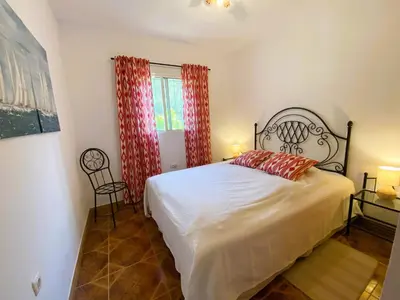 a bedroom with a bed and a window with red curtains at Casa Isabela in Chiclana de la Frontera