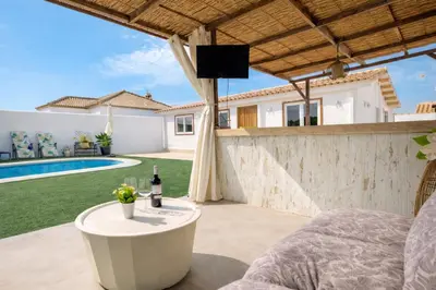 a patio with a table and a tv on a wall at PuraVidaChiclana in Chiclana de la Frontera