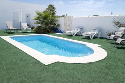 a swimming pool in a yard with green grass at PuraVidaChiclana in Chiclana de la Frontera