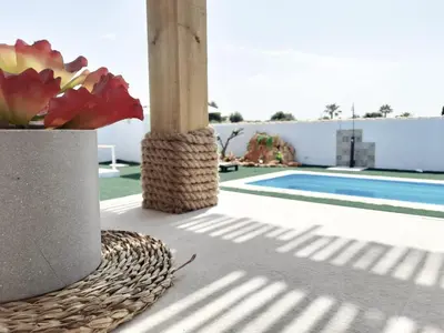 a vase of flowers on a patio with a pool at PuraVidaChiclana in Chiclana de la Frontera