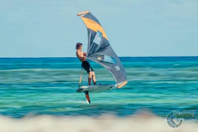 a man on a surfboard with a sail in the ocean at PuraVidaChiclana in Chiclana de la Frontera