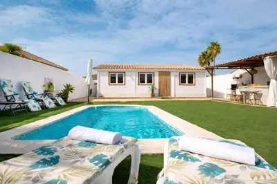 a backyard with a swimming pool and two lounge chairs at PuraVidaChiclana in Chiclana de la Frontera