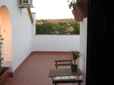 a patio with a bench and a table and a window at El Fogón del Duende in Arcos de la Frontera