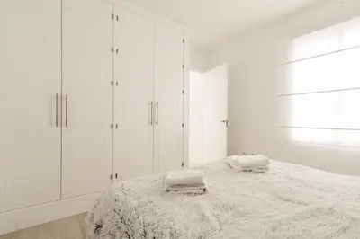 a white bedroom with white cabinets and a bed at Bahía Encanto in El Puerto de Santa María