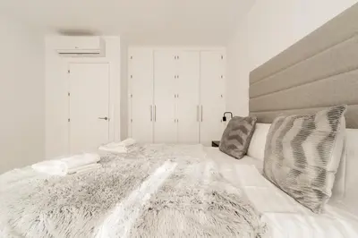 a bedroom with a large white bed with a gray headboard at Bahía Encanto in El Puerto de Santa María