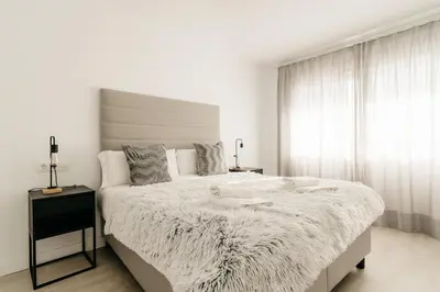a white bedroom with a large bed and a window at Bahía Encanto in El Puerto de Santa María