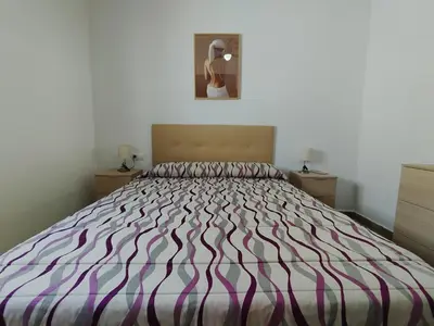 a bedroom with a large bed with a purple and white comforter at Casa Ramos in Conil de la Frontera