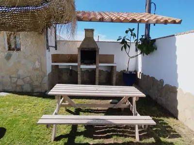 a picnic table with a fireplace in a yard at Casa Ramos in Conil de la Frontera