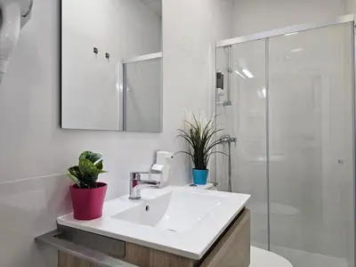 a white bathroom with a sink and a shower at El Anfitrión - Palacio Argüeso in Sanlúcar de Barrameda