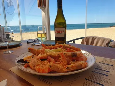 a plate of shrimp on a table with a bottle of wine at El Anfitrión - Palacio Argüeso in Sanlúcar de Barrameda