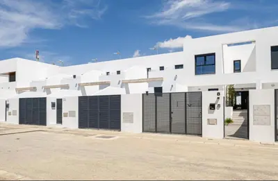 a white building with black gates in a parking lot at Casa Pedro Luis in Conil de la Frontera