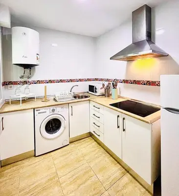 a kitchen with white cabinets and a washer at Apartamento Merykuki in Sanlúcar de Barrameda