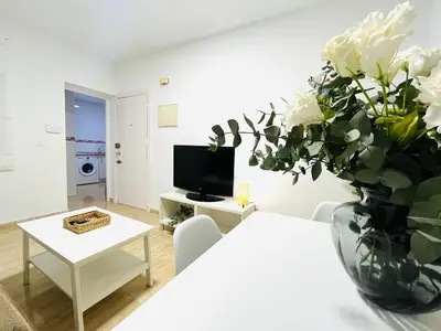 a white living room with a vase of white flowers at Apartamento Merykuki in Sanlúcar de Barrameda