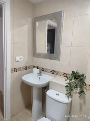 a bathroom with a sink and a toilet and a mirror at Apartamento Merykuki in Sanlúcar de Barrameda