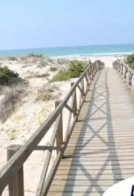 a wooden boardwalk leading to the beach with the ocean at Villa La Vida in Chiclana de la Frontera