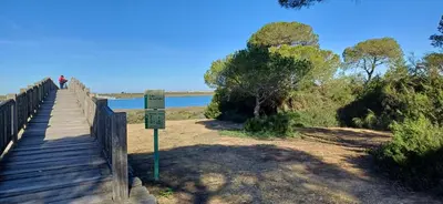 a person walking on a wooden bridge near the water at Apartamento Las Olas de Valdelagrana in El Puerto de Santa María