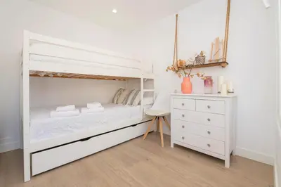 a bedroom with a white bunk bed and a white dresser at La Perla Costera in Chiclana de la Frontera