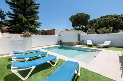 a swimming pool with two lounge chairs and a swimming pool at La Perla Costera in Chiclana de la Frontera