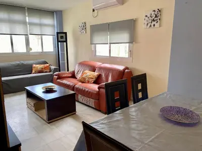 a living room with a red leather couch and a table at APARTAMENTO SALINAS VALDELAGRANA - WiFi, Playa, Piscina in El Puerto de Santa María