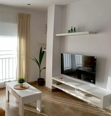 a living room with a large tv and a table at Ático Sol in San Fernando