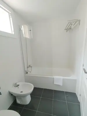a white bathroom with a toilet and a bath tub at Ático Sol in San Fernando