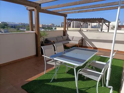 a patio with a table and chairs on a roof at Ático Sol in San Fernando