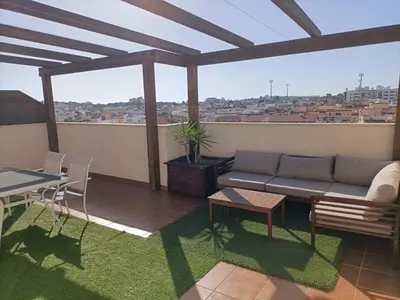 a living room with a couch and a table on a balcony at Ático Sol in San Fernando