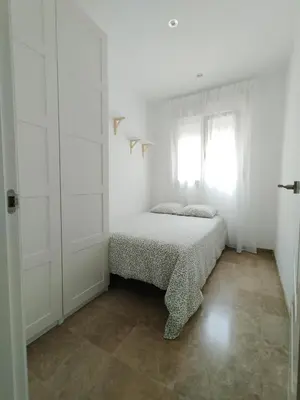 a white bedroom with a bed and a window at Ático Sol in San Fernando