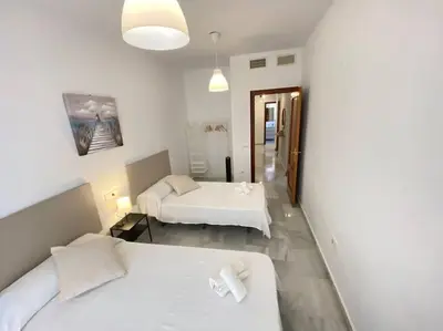 a hotel room with two beds and a hallway at Apartamento en centro con garaje in Sanlúcar de Barrameda
