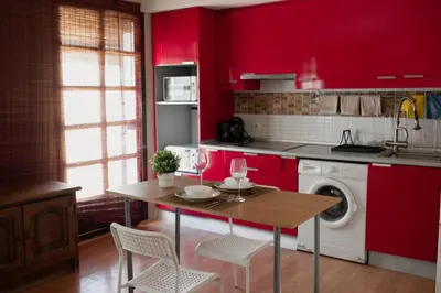 a kitchen with red cabinets and a table with chairs at Apartamento El Catavino in Jerez de la Frontera