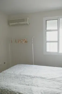 a white bedroom with a bed and a window at Apartamento El Catavino in Jerez de la Frontera
