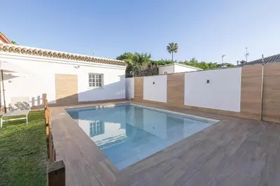 a white bedroom with a bed and two windows at Villa del Sol in Novo Sancti Petri