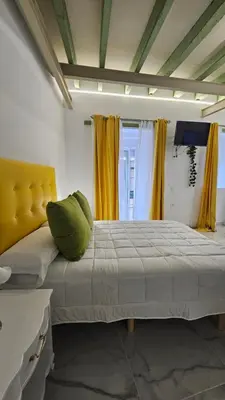 a bedroom with a large bed with yellow curtains at Don Roman Suites en pleno centro by Sanlúcar Housing in Sanlúcar de Barrameda