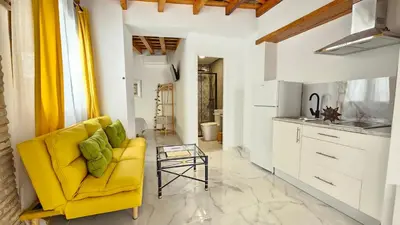 a living room with a yellow couch and a table at Don Roman Suites en pleno centro by Sanlúcar Housing in Sanlúcar de Barrameda