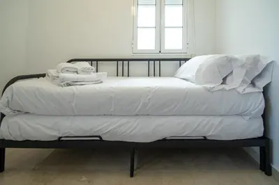 a bed with white sheets and towels on it at Apartamento El Paseo de la Alameda de Cádiz in Cádiz