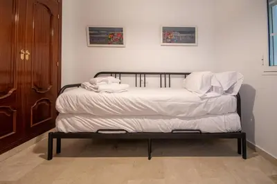 a bed with white sheets and pillows on it at Apartamento El Paseo de la Alameda de Cádiz in Cádiz