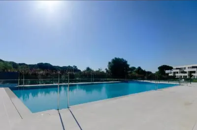 a large swimming pool with blue water at Jardines de Vistahermosa in El Puerto de Santa María