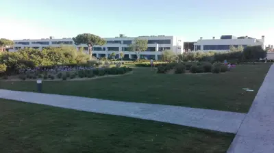 a park with flowers and a building in the background at Jardines de Vistahermosa in El Puerto de Santa María