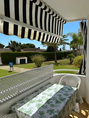 a white bench on a porch with a table and chairs at Apartamento Playa El Manantial in El Puerto de Santa María