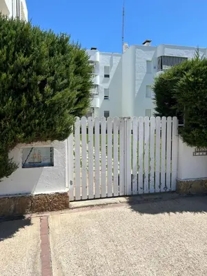 a white fence in front of a building at Apartamento Playa El Manantial in El Puerto de Santa María