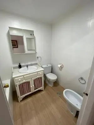 a white bathroom with a sink and a toilet at Apartamento Playa El Manantial in El Puerto de Santa María