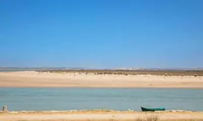 a beach with a green boat in the water at Colibri in Puerto Real