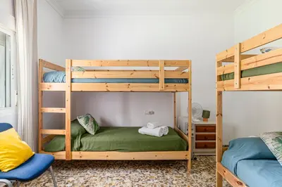 a bedroom with two bunk beds and a chair at Tramontana in Conil de la Frontera