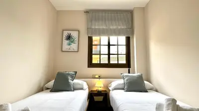 two beds in a small room with a window at Sibs Sanlucar Alcazar - Duplex Recién Reformado in Sanlúcar de Barrameda