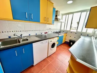 a kitchen with blue cabinets and a white dishwasher at GATU VALDEPLAYA 1ª linea playa piscina parking 3 dormit 2 baños, 