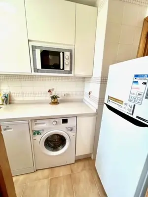a kitchen with a washing machine and a microwave at GATU DULCE junto playa, terraza, aire acc, parking, piscina , 