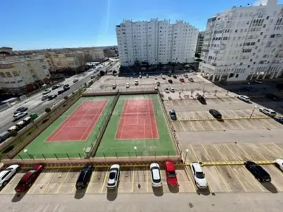 a large parking lot with parked cars in a city at GATU DULCE junto playa, terraza, aire acc, parking, piscina , 