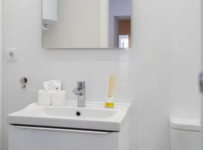 a white bathroom with a sink and a mirror at Estudio Palacios Sur in El Puerto de Santa María