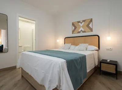 a bedroom with a large bed with a blue blanket at Estudio Palacios Sur in El Puerto de Santa María