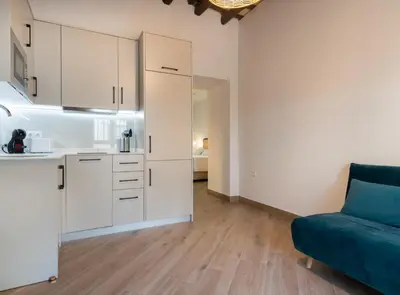 a kitchen with white cabinets and a blue couch in a room at Estudio Palacios Sur in El Puerto de Santa María